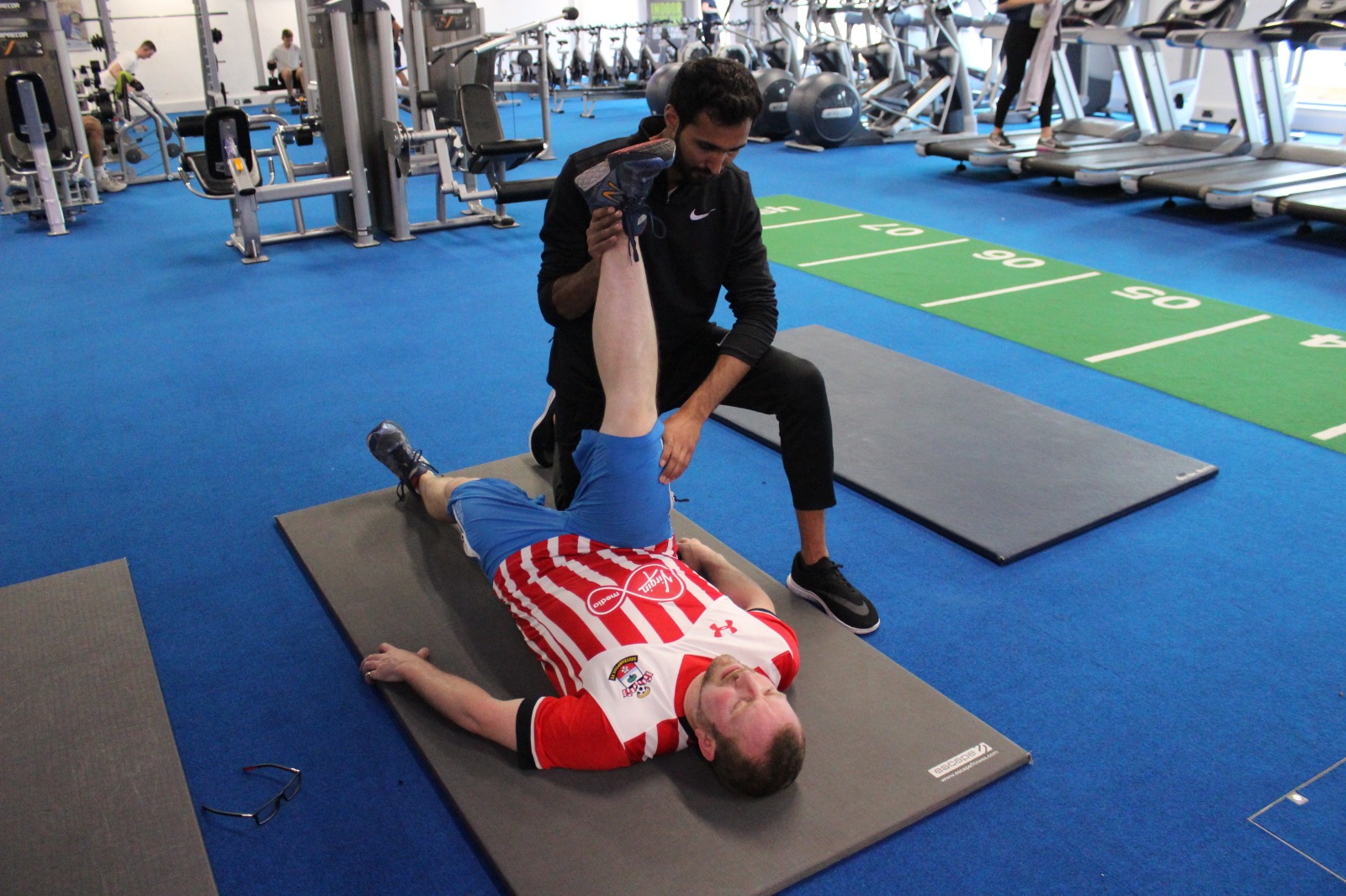 Kam guiding a client through a hamstring stretch